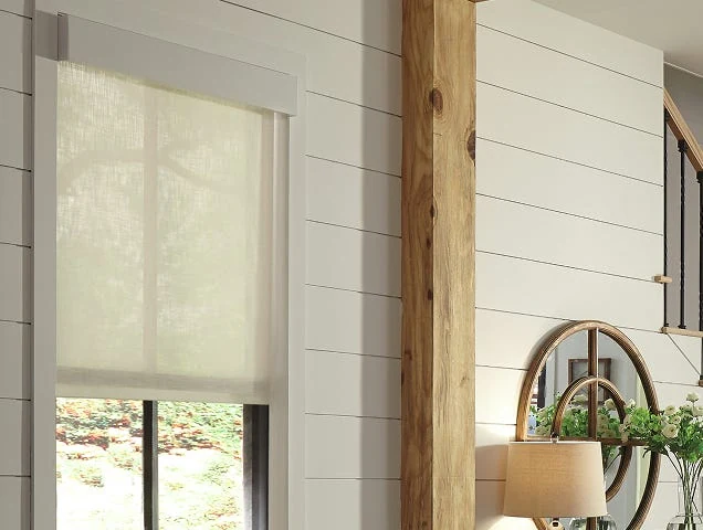 Light-filtering Lutron Serena roller shades lowered across windows beside a white shiplap wall.