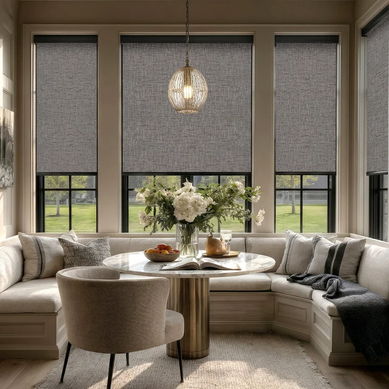 Textured gray SmartWings Safari roller shades lowered over tall windows around a dining nook.